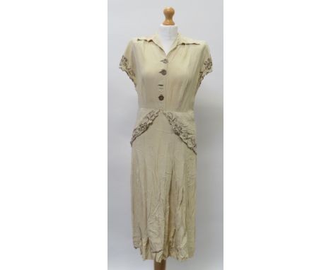 A circa 1930's ladies cream cotton dress with short sleeves, collar, buttons to the front, fitted waist with shaped flounces 