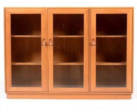 Ercol: an elm Windsor bookcase/display cabinet, with three bevelled glass doors enclosing shelves, 136 x 29 x 98cms high.