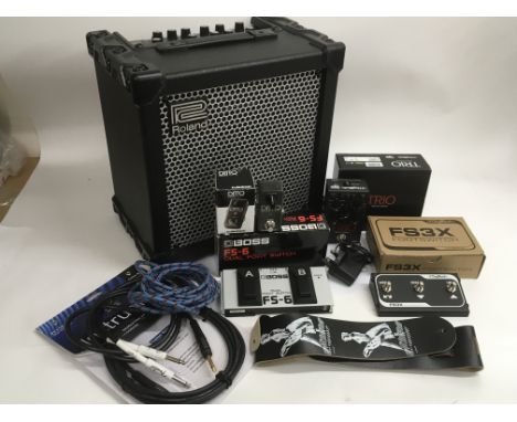 A Roland Cube 40 XL guitar amplifier together with various boxed pedals, guitar leads and a strap. Pedals including a Trio lo