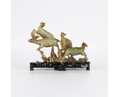 Chinese Republic period jade carving in the form of a group of leaping deer. The carving rests on a carved wood stand and is 