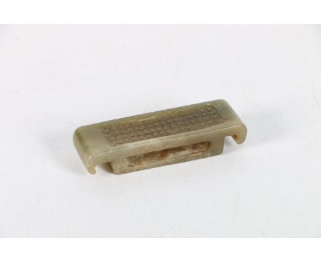 A Chinese grey green jade sword slide with curved ends and carved rice grain decoration to the top, 8cm x 2.5cm 