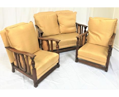 20TH CENTURY OAK SUITEcomprising a two seat sofa and two armchairs, all with shaped backs and outswept arms with shaped caned