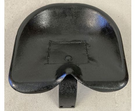 A vintage large metal tractor seat painted black.  