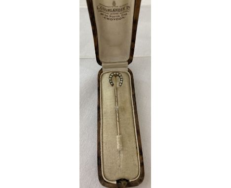 A vintage gold horseshoe stick pin set with 12 seed pearls. In a period stick pin box. Tests as 9ct gold. Total weight approx
