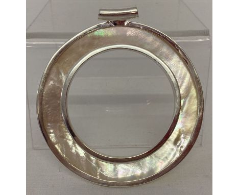 A large circular shaped double sided mother of pearl pendant. Marked 925. Approx. 6.75cm diameter.