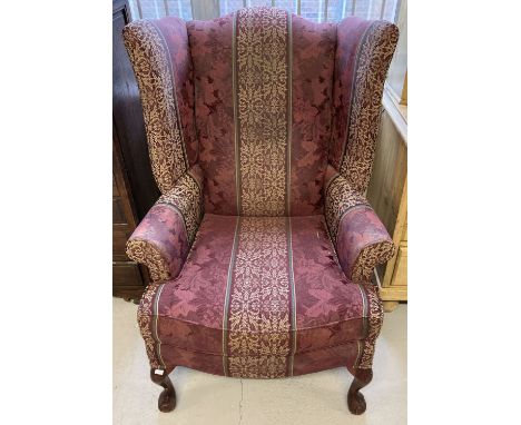 A vintage wing back arm chair with cabriole style legs with ball and claw carved feet. Burgundy, green and gold upholstery. 