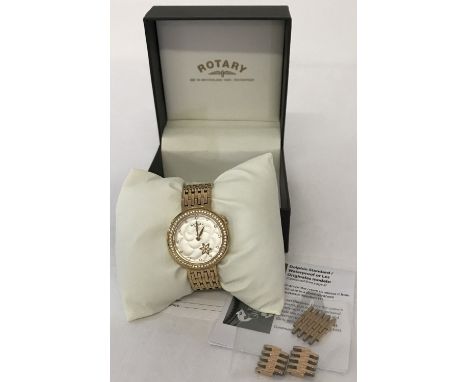 A ladies modern wristwatch by Rotary. Cushion style satin finish white face with gold tone flower. Gold tone case with clear 