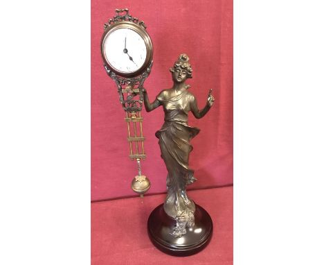 A bronze based figural, swinging pendulum mystery clock. In the form of an Art Nouveau style woman, mounted on a wooden circu