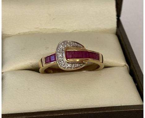 A 9ct gold ruby and diamond set buckle design dress ring, possibly Luke Stockley, London. 7 square cut channel set rubies wit