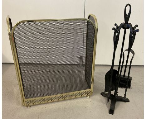 A pained black wrought iron companion set together with a decorative fire guard with pierced brass work decoration. Fireguard