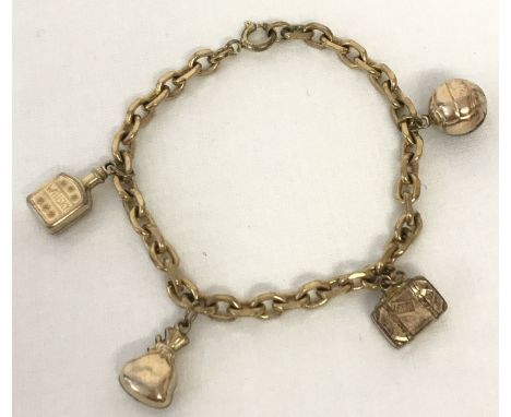 A vintage rolled gold charm bracelet with 4 charms. A whisky bottle, suitcase, football and a sack. Fixings marked 'Germany R