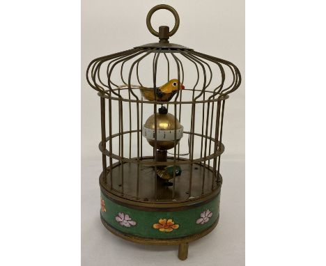 An ornamental wind up birdcage clock with cloisonné panel to base. The cage features two small feathered birds which rotate w