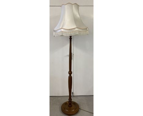 A modern dark wood standard lamp with carved channelled detail. Complete with cream coloured, tasselled shade. 