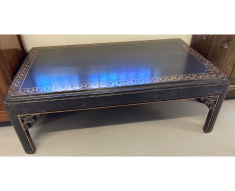 A very large vintage dark wood coffee table with carved detail and gilt painted design to top.  Approx. 45cm tall x 126cm lon