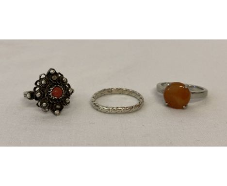 3 silver and white metal dress rings. An orange jade solitaire and a twist design band. Together with a filigree detail ring 