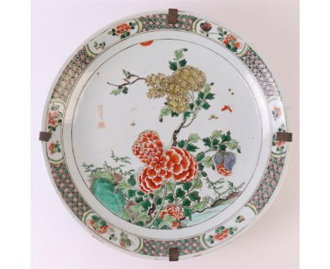 A porcelain famille verte dish, China, Kangxi, around 1700. Polychrome decor of peonies and flora on a rock and insects in th