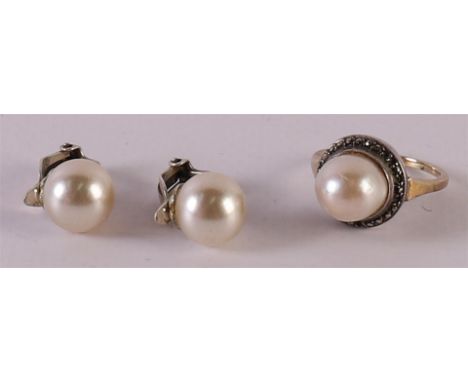 An 8 kt 333/1000 BWG gold ring, set with a pearl, Ø 17 mm, gross weight 4.5 grams. Here is a pair of silver ear clips with pe