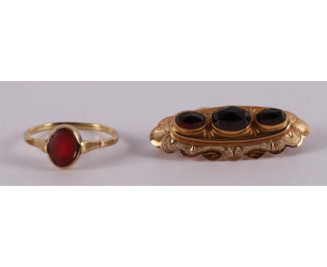 A 14 kt 585/1000 gold contoured brooch, set with three faceted garnets, gross weight 3.4 grams, l 3.5 cm. Here is ditto gold 