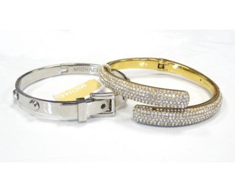 TWO MICHAEL KORS BANGLEScomprising a brilliance statement bangle in gold tone with pave stones, and a silver tone buckle desi