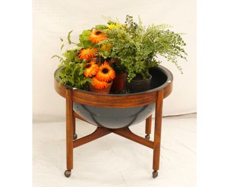 RETRO ROSEWOOD CIRCULAR PLANTER
with a plastic domed liner, standing on turned supports with castors united by a stretcher, 6