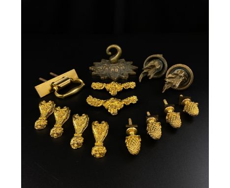 A collection of brass and gilt metal fixings to include four cup and cover handles, a swing handle, eight decorative mounts a