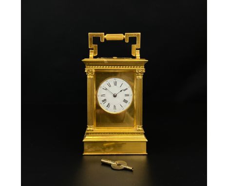 A 20th century brass carriage clock with a shaped swing handle over a moulded cornice with a dial bearing Roman numerals enca
