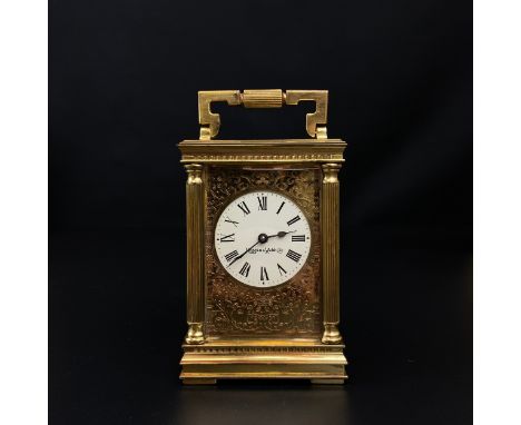 A 20th century brass Mappin &amp; Webb carriage clock having a shaped swing handle above a moulded cornice over a pierced and