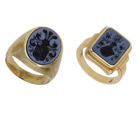 Two hardstone signet rings, each inset with an oval or rectangular hardstone panel with armorial crest seal engravings, stamp