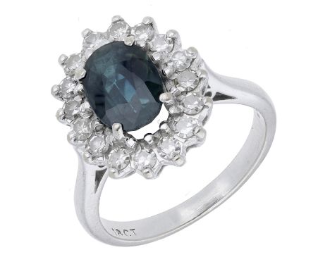 A sapphire and diamond cluster ring, the oval-cut sapphire within a surround of single-cut diamonds, stamped ‘18CT’, total di