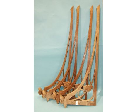 A set of four hardwood Art Nouveau wall brackets decorated with stylised flower heads, 108cm long, 37cm high, (4).