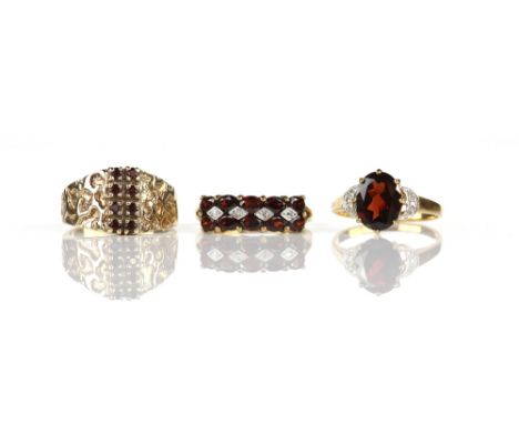 Three garnet rings, comprising a garnet and diamond half hoop ring, set with ten oval cut garnets, with single cut diamond de