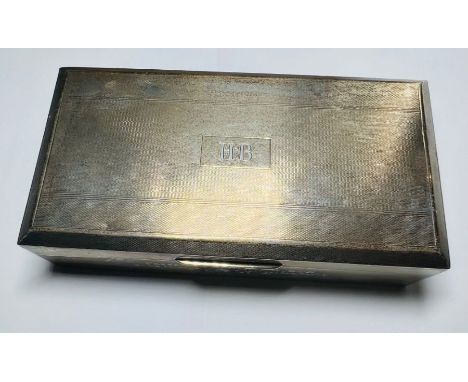 A hallmarked silver box, hinged, with engine turned lid. On the top is an inscription, H.B. and at the front side, the words 