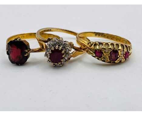 A trio of dress rings featuring red stones, comprising: Asingle stone dark red paste ring in 18ct gold, size R, approximate g