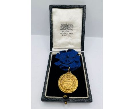 A 9ct gold public school medal on decorative blue rosette. A Woodside H.G. Public School War Memorial Medal. Awarded to Willi