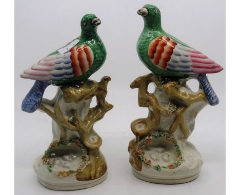 A pair of mid 19th Century Staffordshire figures modelled as stylised birds seated to tree boughs&nbsp; with nest of eggs bel