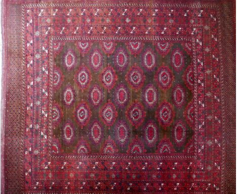 A large Turkmen Bokhara carpet, with central repeating geometric motifs on a red ground, contained by repeating geometric bor