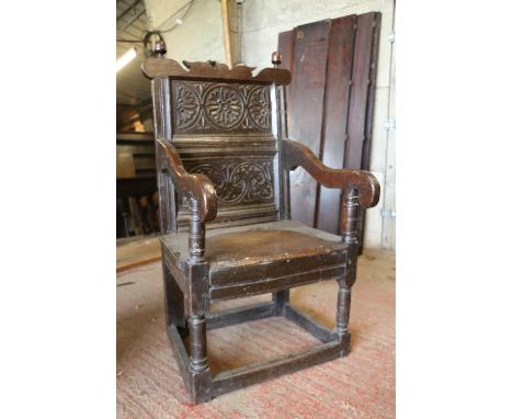 17th century wainscot chair, the foliate carved panel back with acorn finials, above solid seat, shaped arms, raised on turne