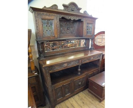 A Victorian oak sideboard with leaded light doors, carved leaf and lion mask decoration and mirror back