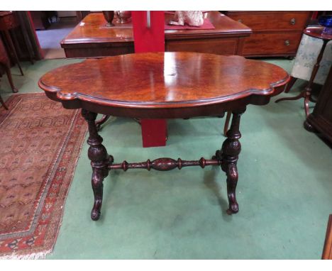 Circa 1850 a burr walnut table the shaped top on turned and carved supports with scroll foot legs joined by a stretcher over 