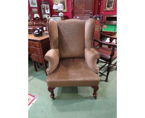 A 19th century walnut wing back fireside armchair the scroll arms over pad foot cabriole legs and ceramic castors, 105cm tall