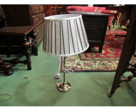 A brushed metal table lamp with pleated shade
