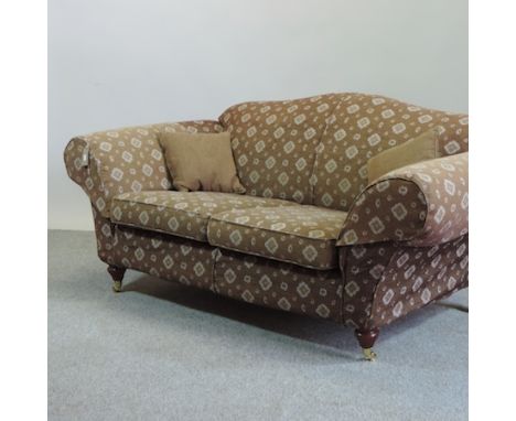 A brown upholstered two seater sofa, on turned legs and castors, 180cm