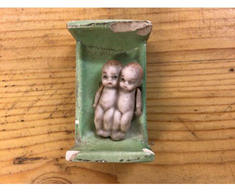 Dolls - German Bisque Conjoined miniature twins with pin jointed arms, in miniature green ceramic bed.