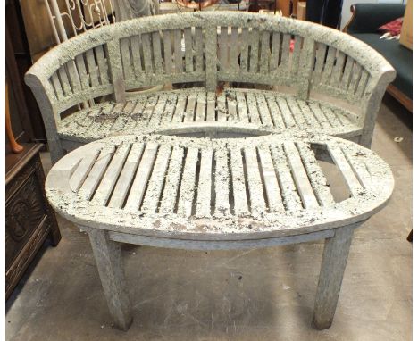 A weathered teak slatted kidney-shaped garden bench, 160cm wide and a matching table, 117 x 56cm. 