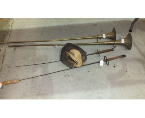 A vintage fencing face guard, two fencing foils and two brass coaching horns. 