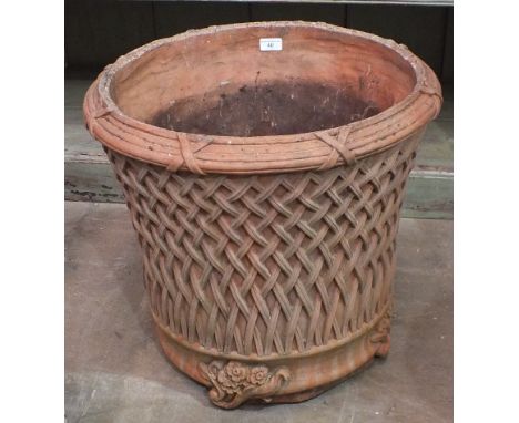 A modern terracotta planter decorated with lattice work, on foliate feet, 52cm high, 54cm diameter. 