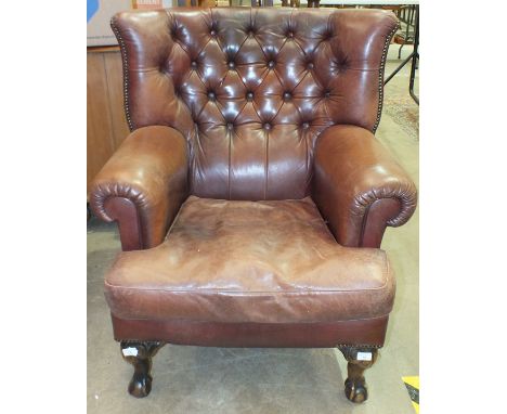 A modern leather upholstered armchair on stained wood claw and ball feet, with button back, (soiled). 