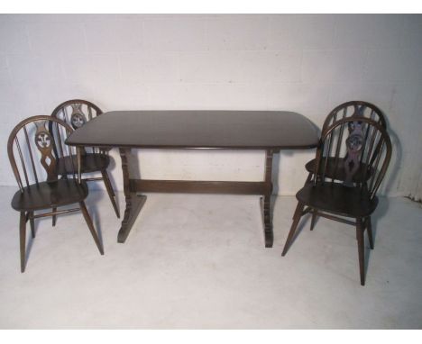 An Ercol dark wood refectory table, with four matching Ercol stick back chairs, includes four poppy design seat cushions.