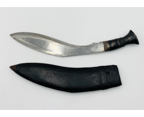 A vintage Kukri knife in leather sheath, the handle decorated with brass and steel