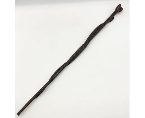 A carved walking stick with fist pommel and entwined snake